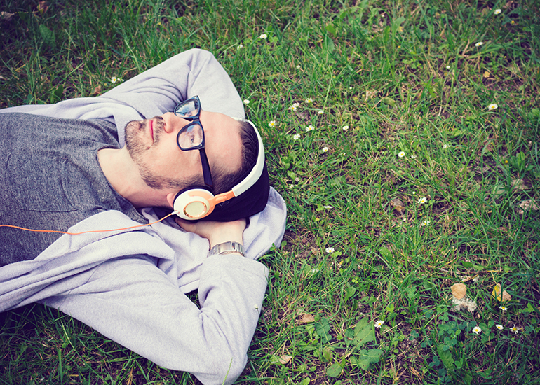 man relaxing on grass with headphones