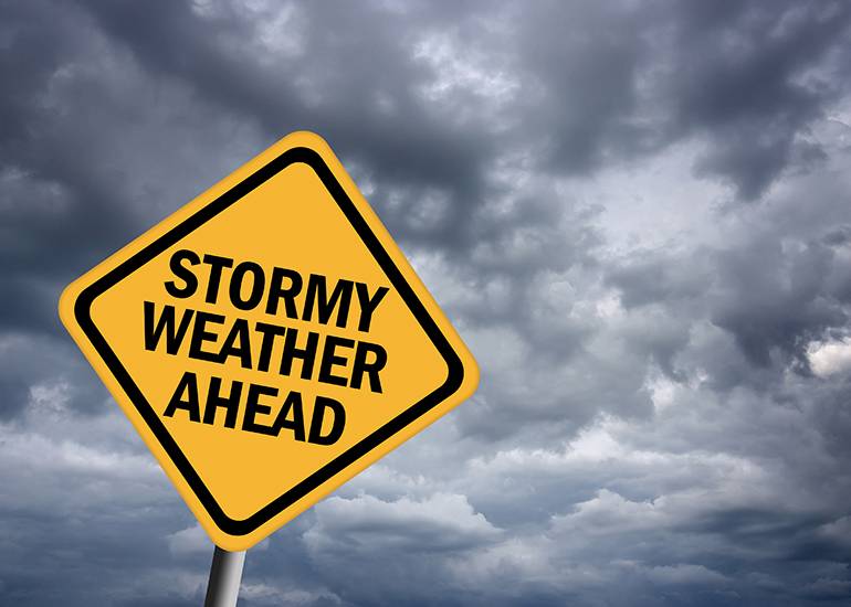 'Stormy weather ahead' sign on dark clouds background