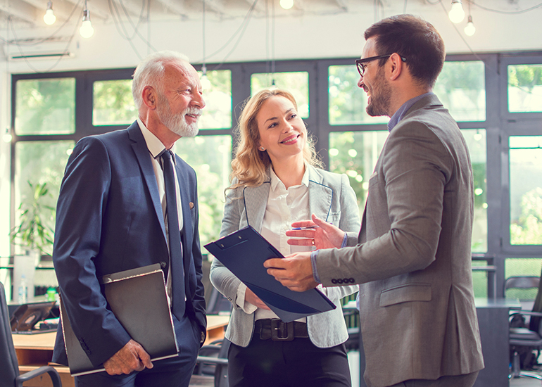 Mature-aged businessman talking with younger colleagues in office