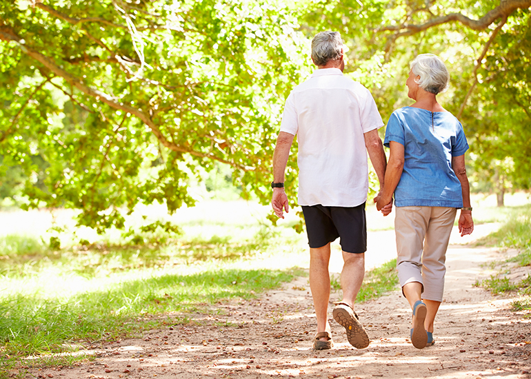 Retired couple holding hands and walking outdoors