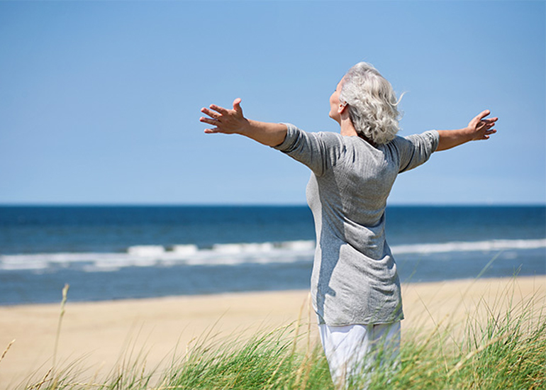 happy retired older woman on beach