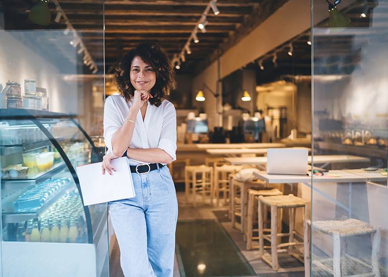 Female business owner standing at door of her restaurant