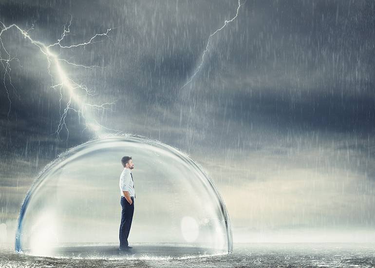 Businessman standing in protective bubble amidst storm