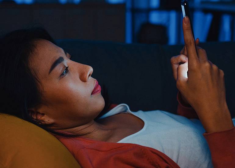 woman scrolling phone in bed at night