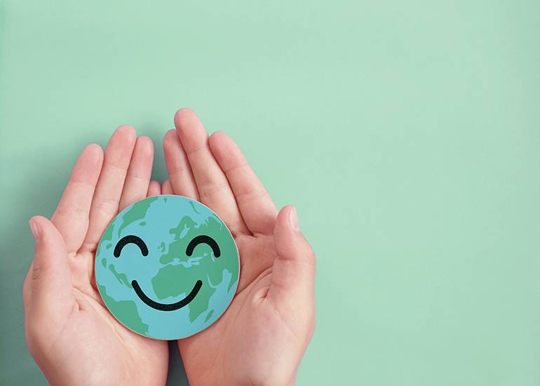 hands holding a paper earth globe with smiling face