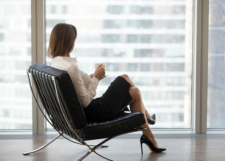 well-dressed business woman sitting in office drinking coffee