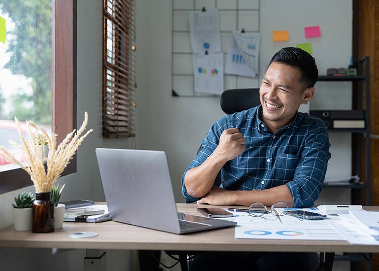 Happy man at desk celebrating success