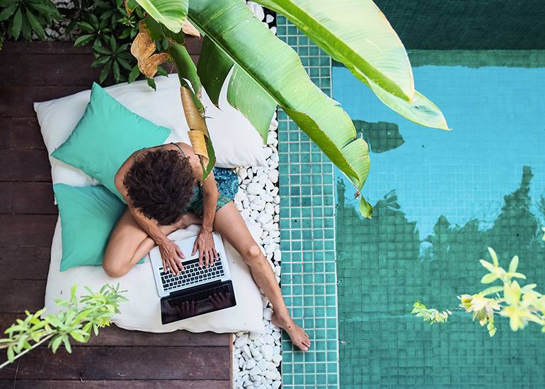 Woman working beside pool at holiday resort