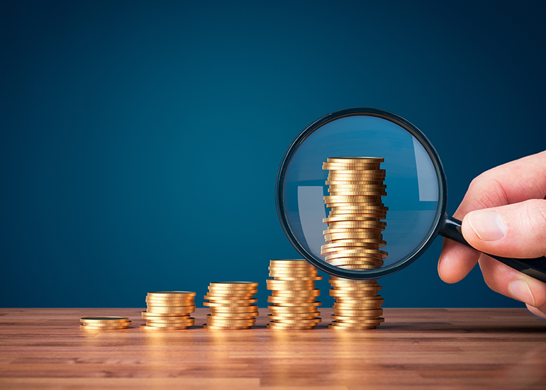 Magnifying glass highlighting the tallest stack of coins in a row