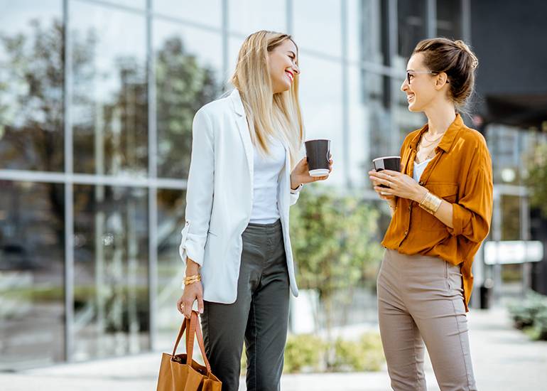 Two women having a conversation with takeaway coffee