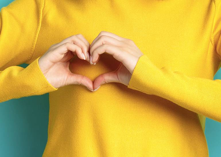 Woman forming a love heart with her hands in front of her heart