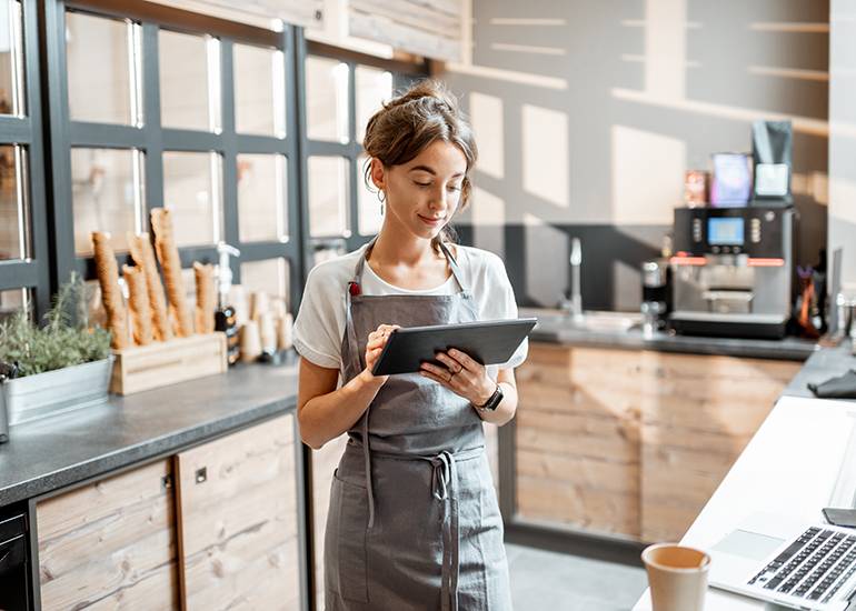 young female worker or cafe owner using digital device