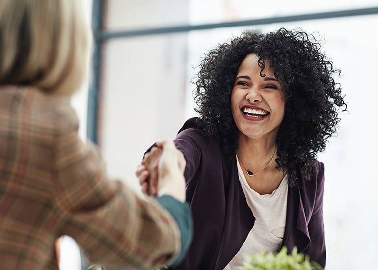 Two women shaking hands in meeting