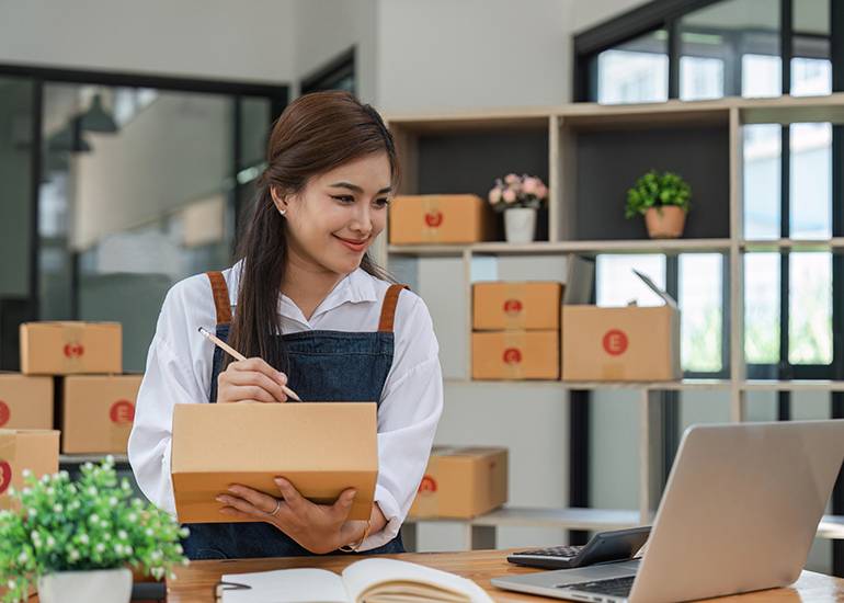 Woman writing on package in workshop
