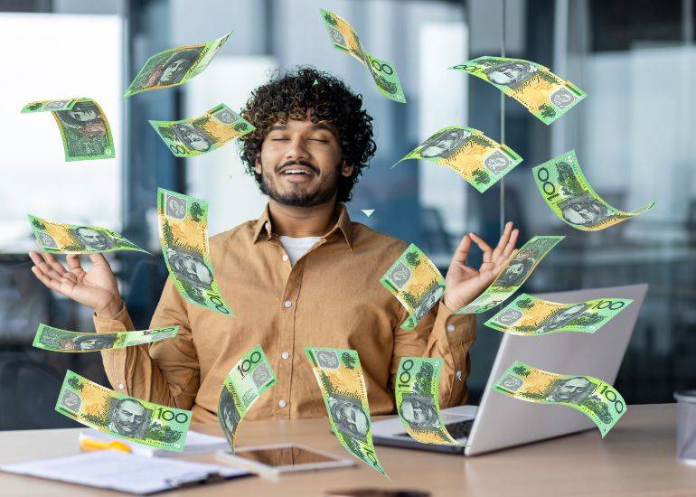 cultivate a money mindset- man mediatating at desk as money showers around him