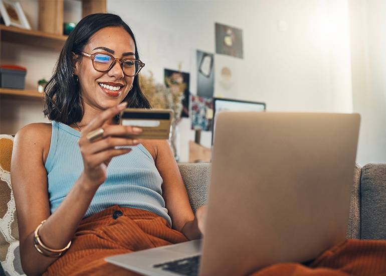 Customer Shopping concept: Woman on couch with laptop, credit card and online shopping