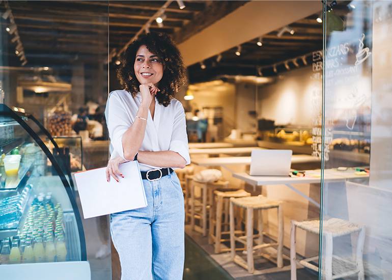 franchise concept: woman stands in front of a shop smiling