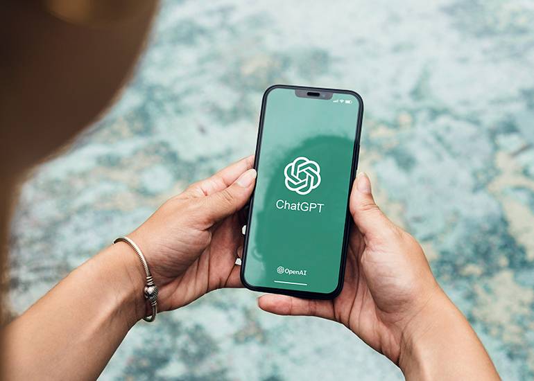 chatgpt concept: a hands holding a mobile phone on the screen is a logo displaying the words Chatgpt