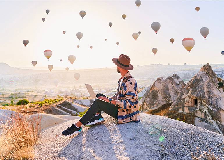 long-form content- traveller sits on the top of a mountain creating content on their laptoip