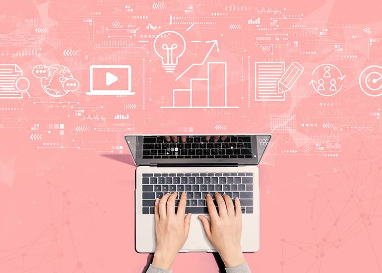 content marketing concept hands typing on a laptop icons for different type of content float in the air.