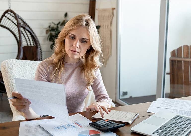 a solo business owner woman with blonde hair sits at desk looking at paperwork