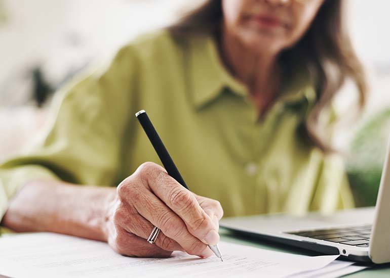 woman at. computer looking over data writing up her superannuation retirement plan